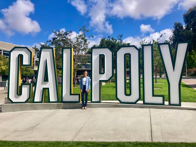 Dr. Delaney Dann standing in front of the Cal Poly sign